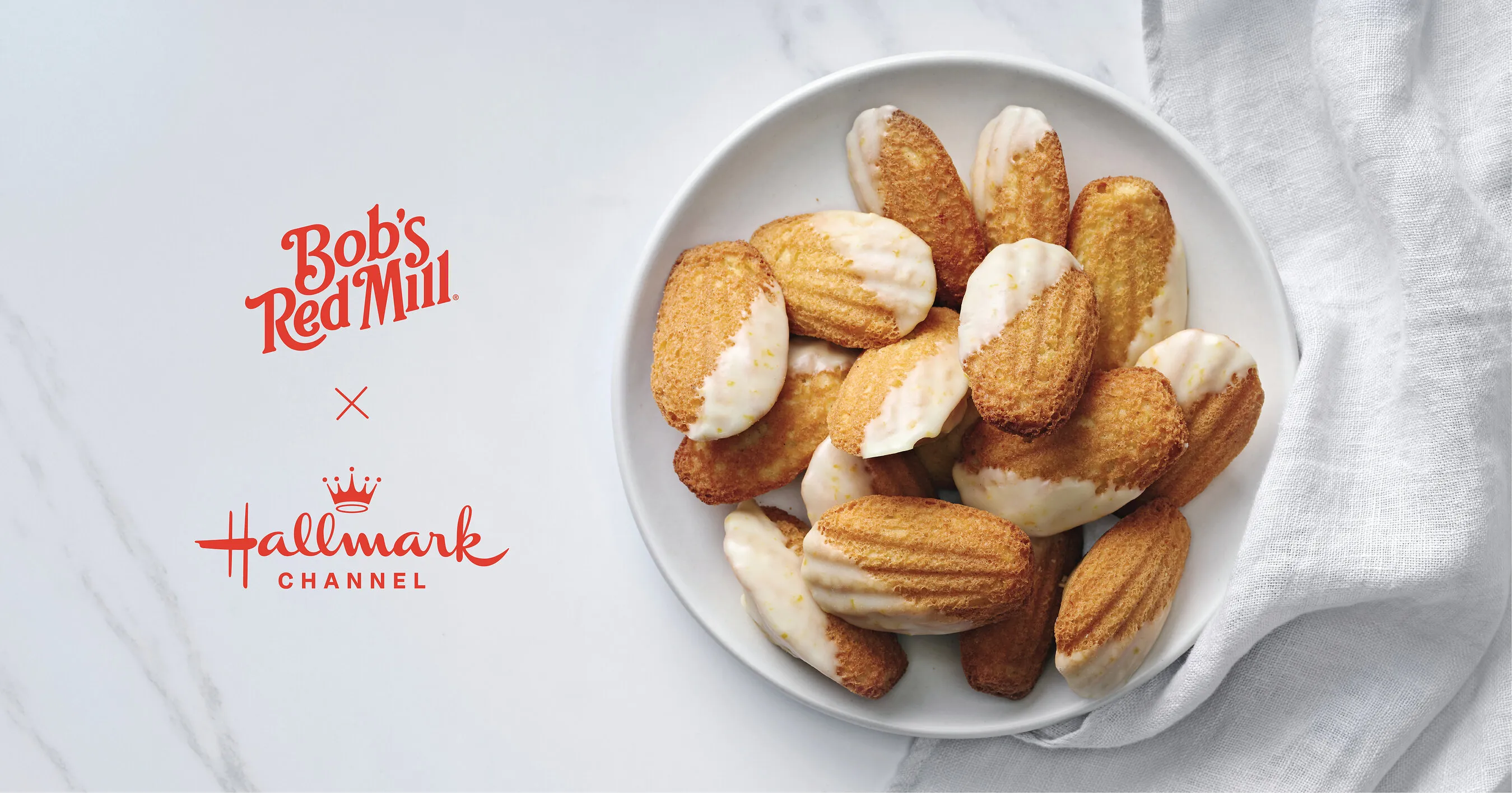 Bob’s Red Mill and Hallmark Channel logos beside a bowl of iced madeleine cookies.