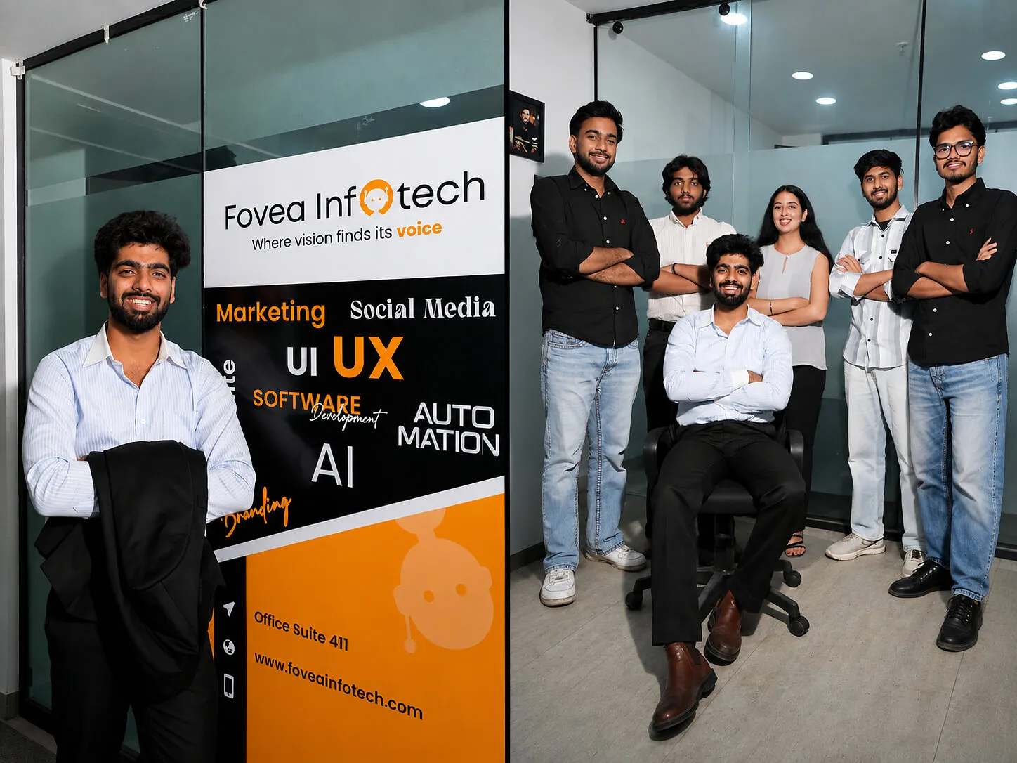 A man stands beside a Fovea Infotech sign, and six people pose together in an office.