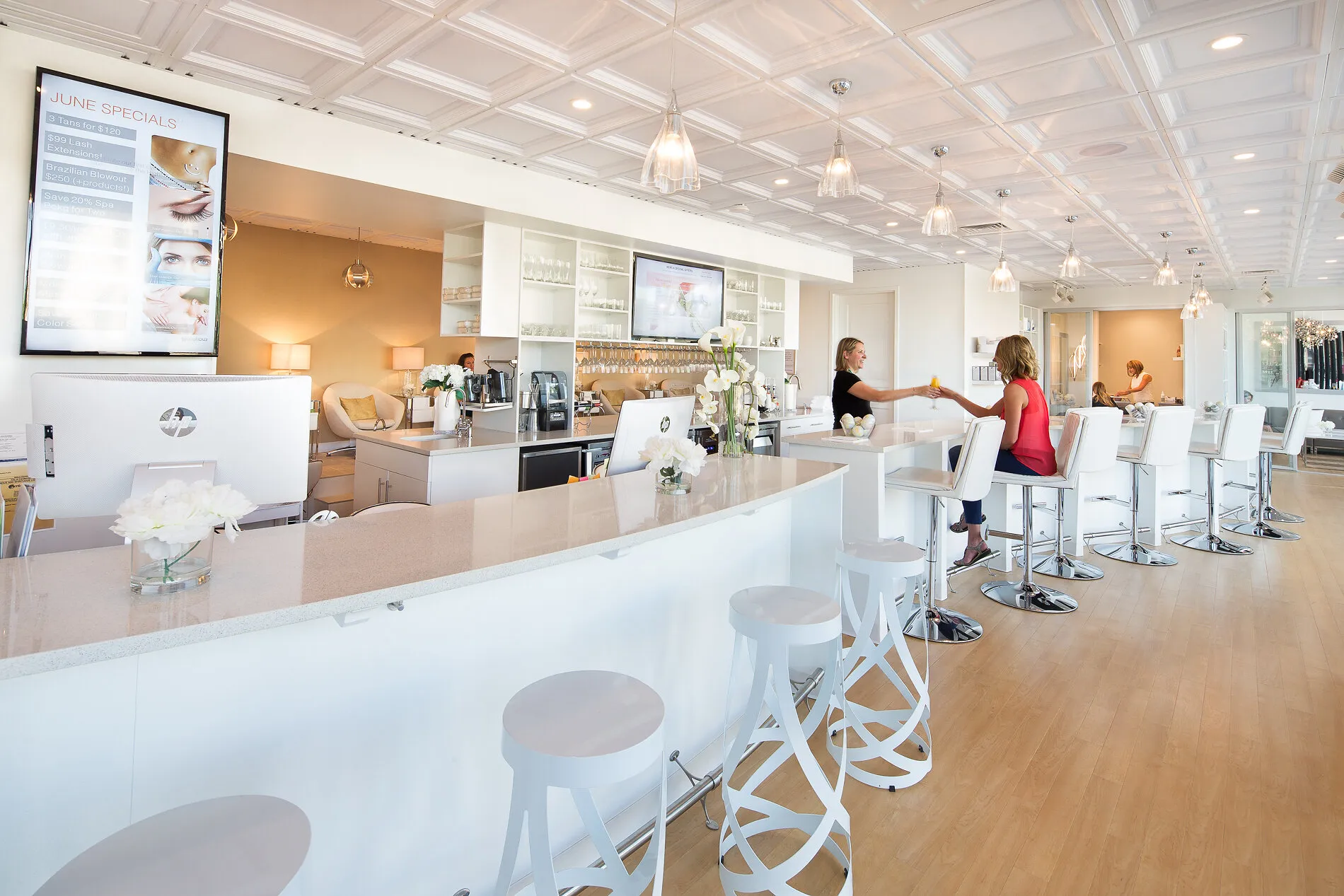 Bright white aesthetic bar interior with staff and customers seated at high counters.