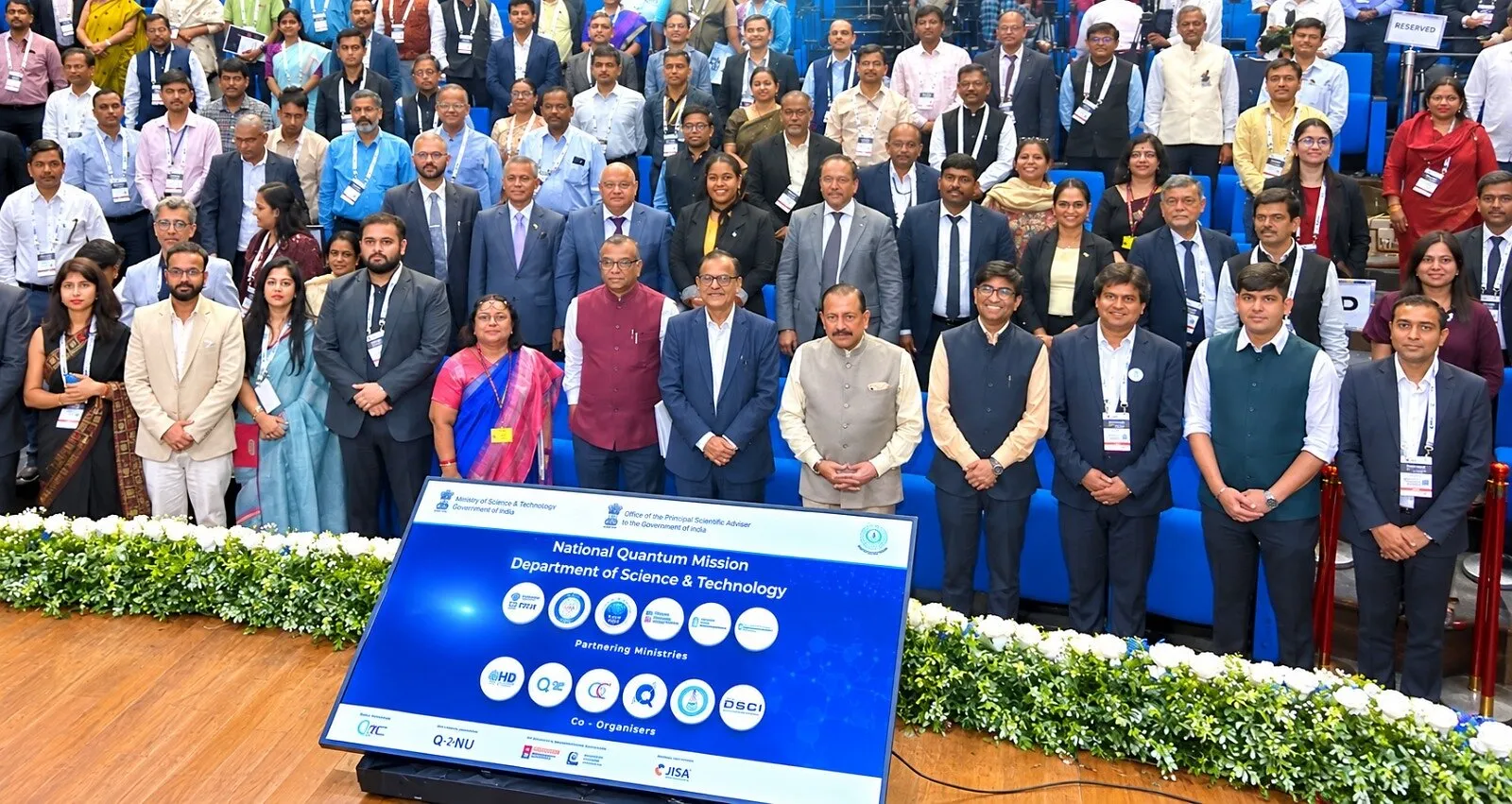 Group of attendees standing behind a National Quantum Mission sign at a conference.