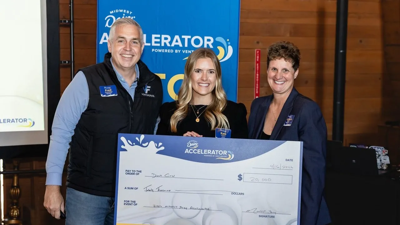 Three people hold a ceremonial $20,000 check at a Midwest Dairy Accelerator event.
