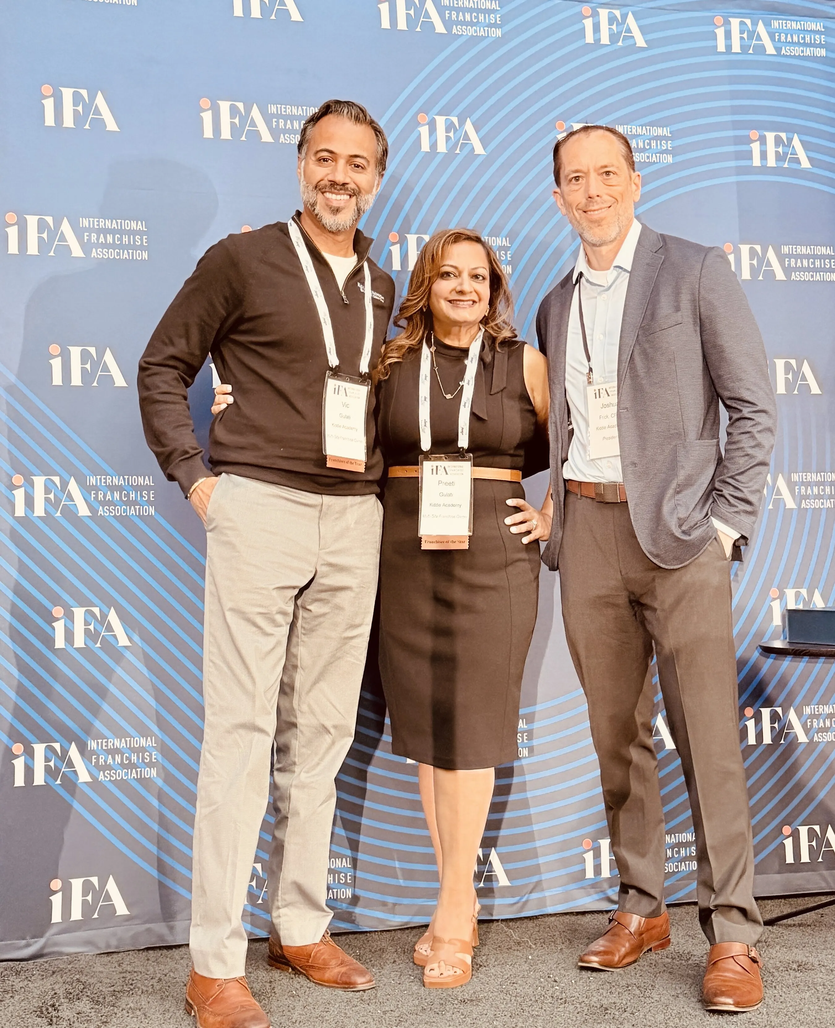 Vic Gulati, Preeti Gulati and Josh Frick at an International Franchise Association backdrop.