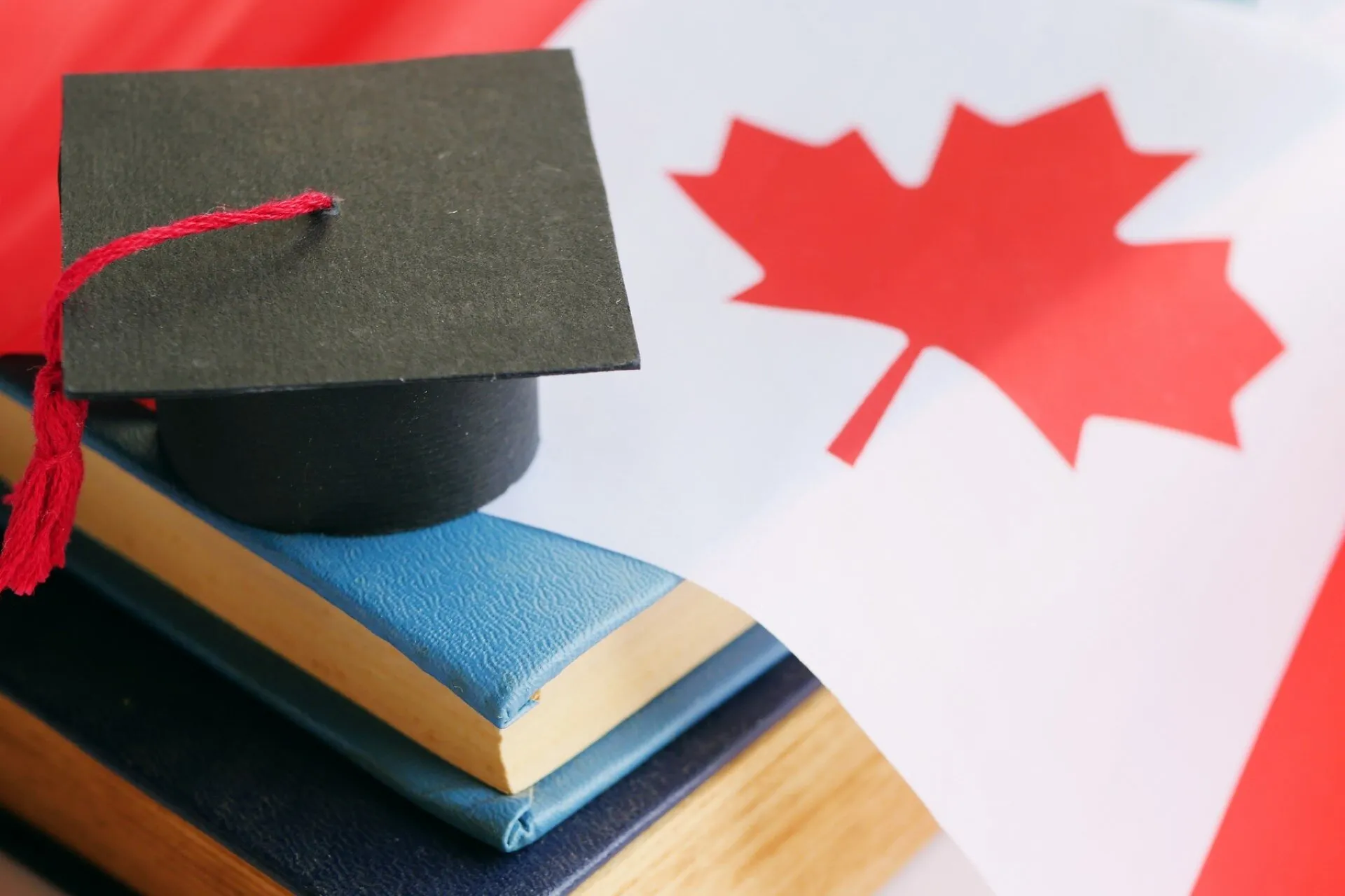 A graduation cap on books beside a Canadian flag