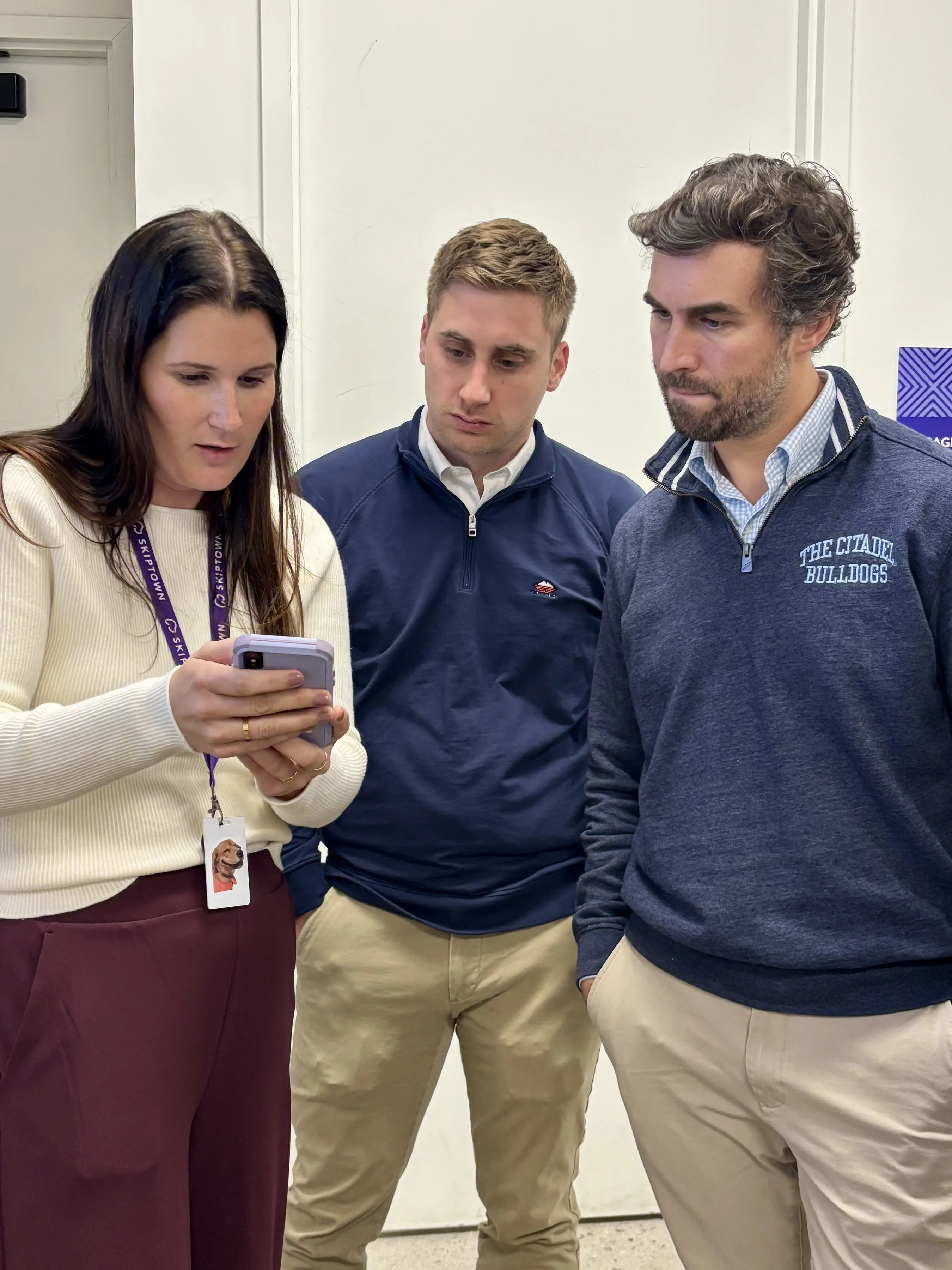 Three people looking at a smartphone.