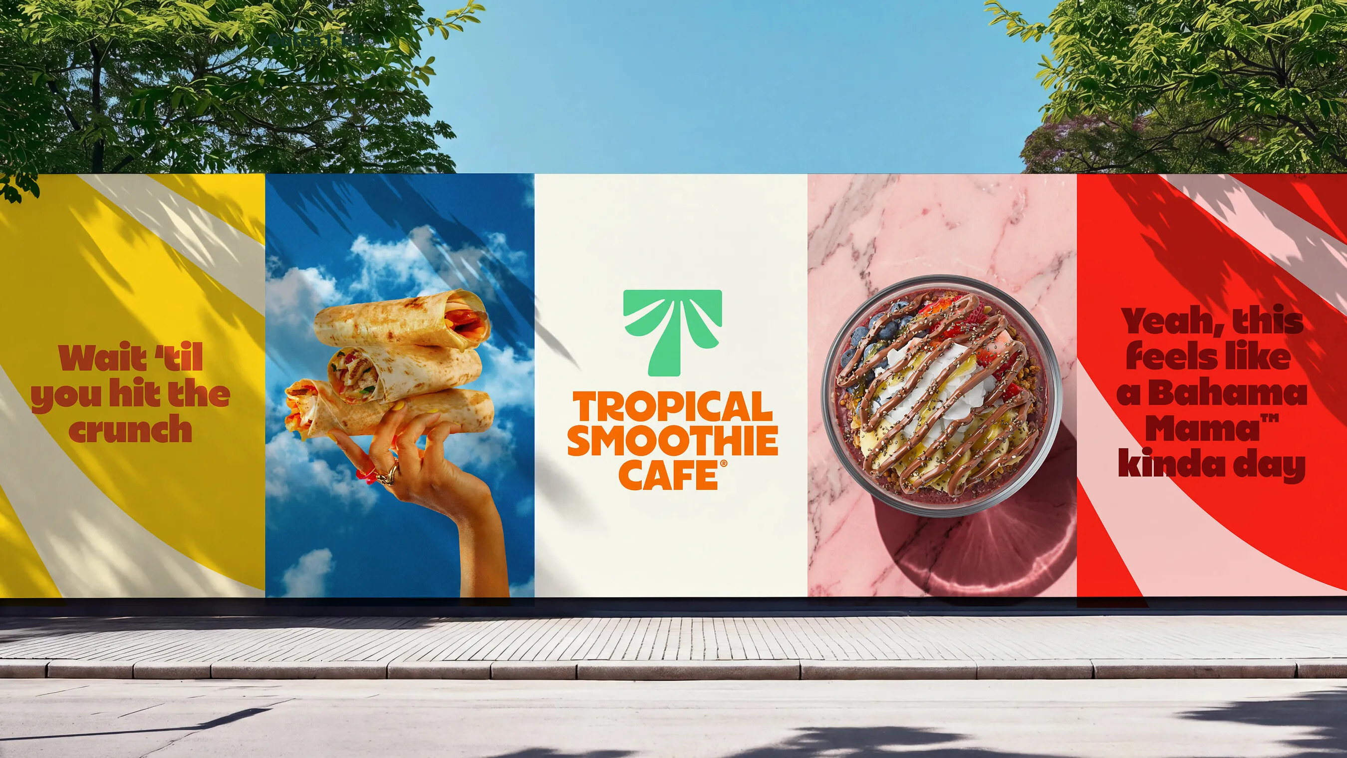 Tropical Smoothie Cafe posters along a street wall showing wraps, a smoothie bowl, the new logo and colorful slogans.