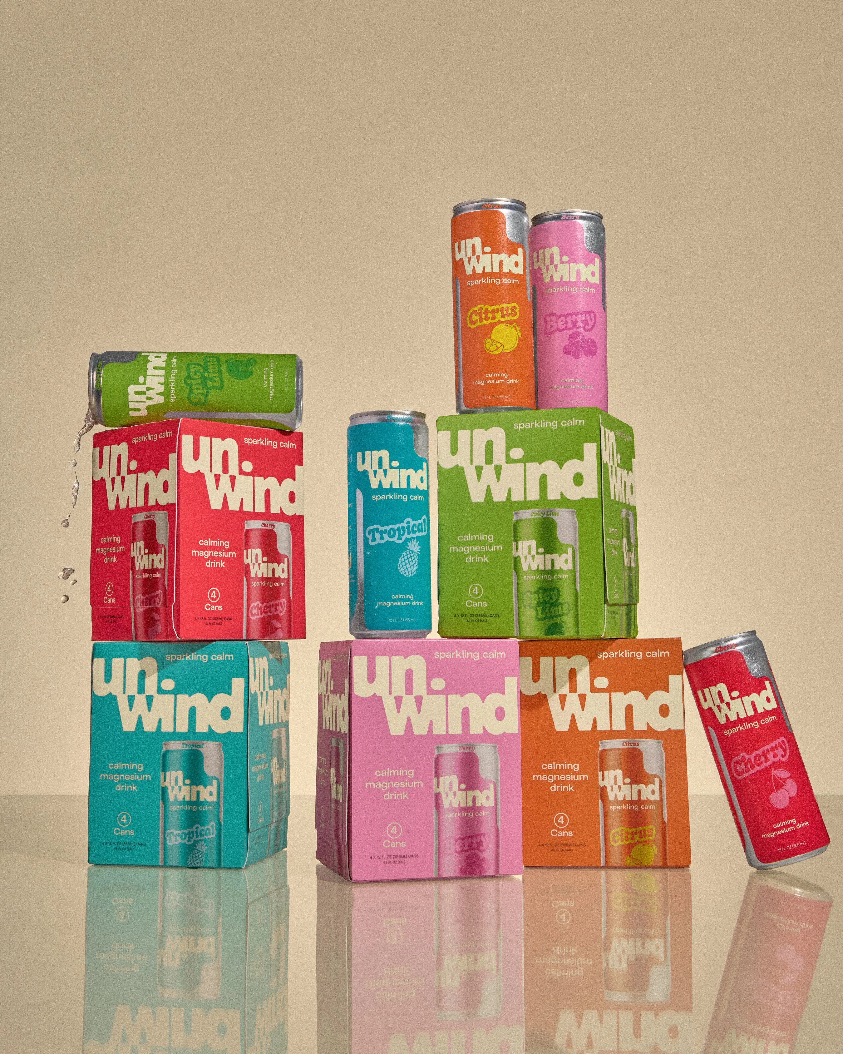 Colorful Unwind sparkling calm drink cans and four-packs stacked on a reflective surface.