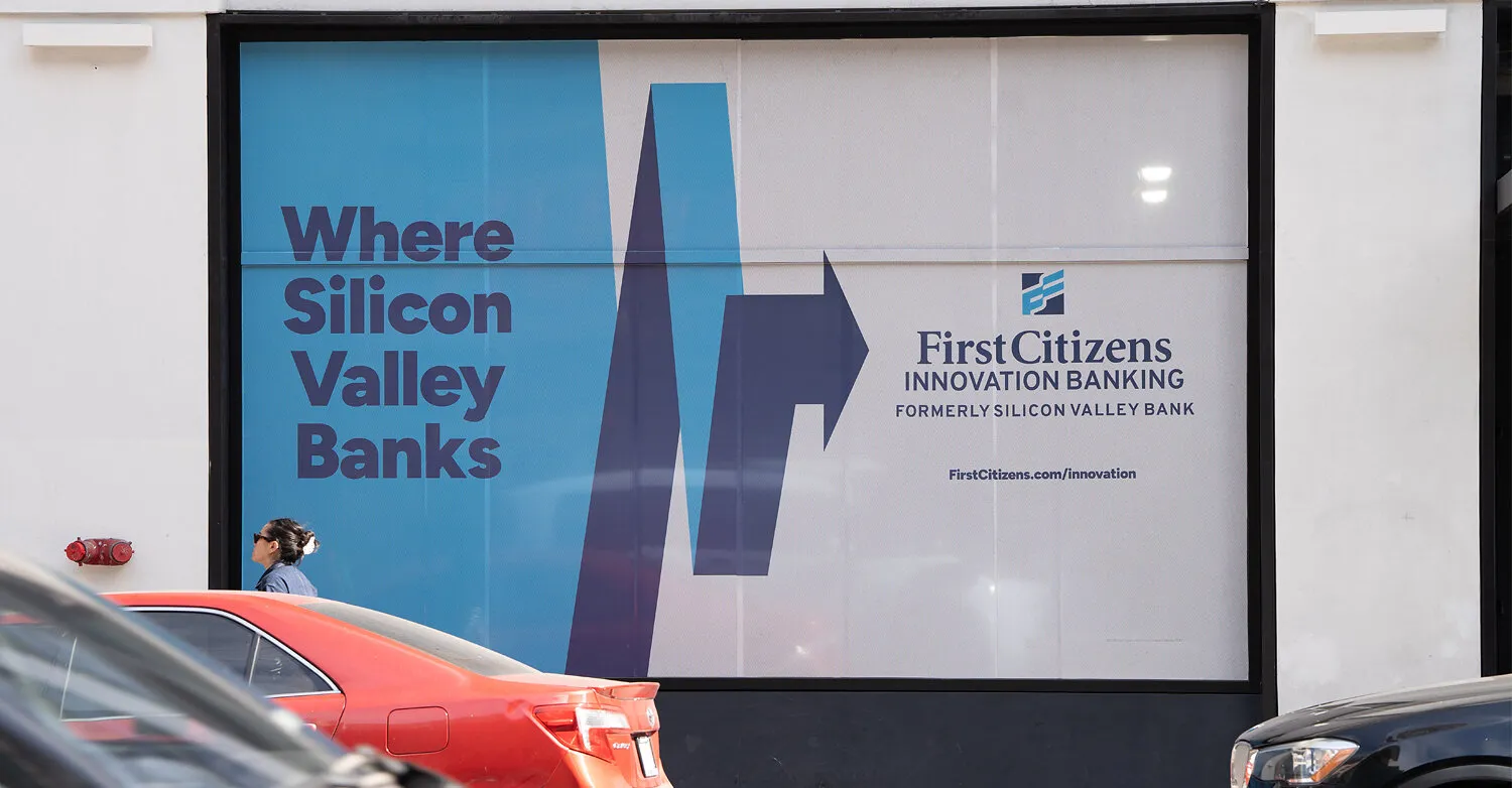 A Where Silicon Valley Banks poster for First Citizens Innovation Banking, with parked cars and a pedestrian in front.