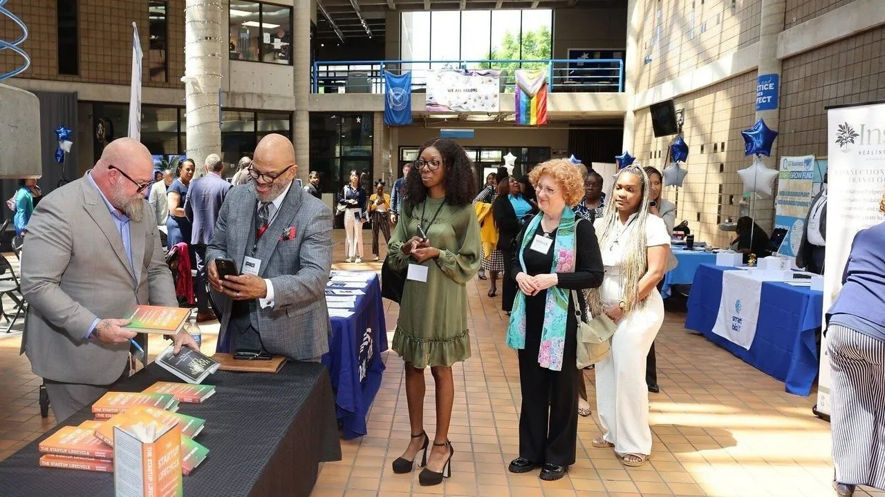 People browse book displays at an indoor networking event.