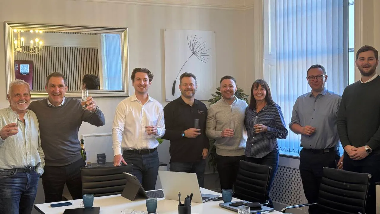 Eight members of the Vantage Waste Solutions team stand around a meeting table raising glasses in an office.